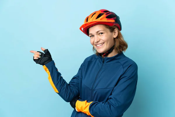 Молода Жінка Велосипедистка Ізольована Синьому Фоні Вказуючи Пальцем Бік — стокове фото