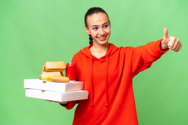 Genç bir Arap kadını, izole edilmiş geçmişinden dolayı fast food tutuyor ve iyi niyet gösterisi yapıyor.