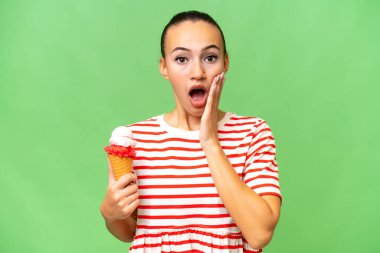 Kornet dondurması ile izole edilmiş bir arka planı olan genç bir Arap kadın şaşırmış ve şok olmuş bir yüz ifadesi var.