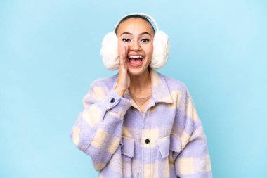 Mavi arka planda izole edilmiş, ağzı açık bağıran genç bir Arap kadın.