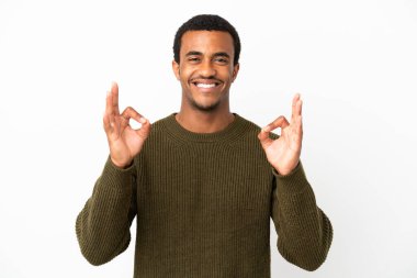 İzole edilmiş beyaz arka planda Afro-Amerikalı yakışıklı bir adam iki eliyle tamam işareti gösteriyor.