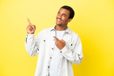 İzole edilmiş sarı arka planda Afro-Amerikalı yakışıklı bir adam işaret parmağıyla işaret etmek harika bir fikir.