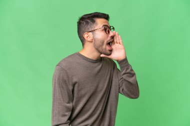 Tecrit edilmiş arka planda genç, yakışıklı beyaz bir adam ağzı sonuna kadar açık bağırıyor.