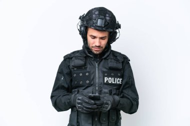Beyaz arka planda izole genç beyaz SWAT adamı cep telefonuyla bir mesaj gönderiyor