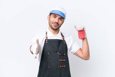 Kasap beyaz önlük giymiş ve izole edilmiş beyaz arka planda taze et servis ediyor. İyi bir anlaşma için el sıkışıyor.