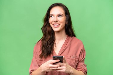 Kafkasyalı genç bir kadın izole edilmiş arka planda cep telefonu kullanıyor ve