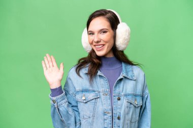 Kafkasyalı genç bir kadın, izole edilmiş arka planda kışlık kuklalar takıyor ve mutlu bir ifadeyle selamlıyor.