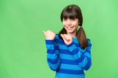 İzole edilmiş arka planda küçük beyaz bir kız bir ürün sunmak için kenarı işaret ediyor.