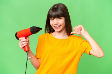 Kafkasyalı küçük bir kız izole edilmiş arka planda saç kurutma makinesini tutuyor gururlu ve kendinden memnun.