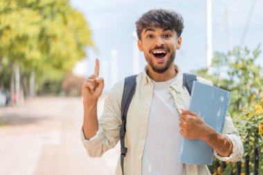 Genç Arap öğrenci açık havada harika bir fikri işaret ediyor.