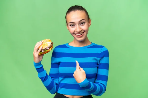 Young Arab Woman Holding Burger Isolated Background Surprise Facial Expression —  Fotos de Stock