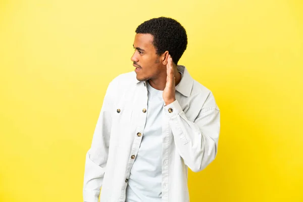 Afrikkalainen Amerikkalainen Komea Mies Eristetty Keltainen Tausta Kuuntelee Jotain Laittamalla — kuvapankkivalokuva
