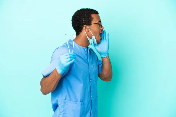 Africký Americký Zubař Drží Nástroje Přes Izolované Modré Pozadí Křičí — Stock fotografie