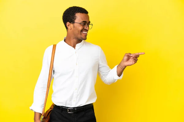 African American business man over isolated yellow background pointing finger to the side and presenting a product