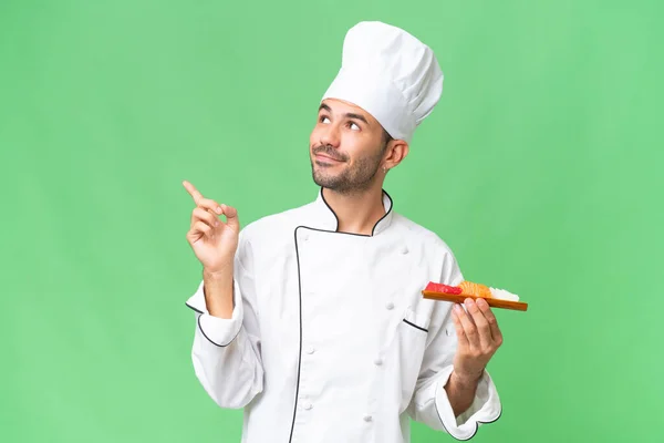 Jonge Kaukasische Chef Houdt Een Sushi Boven Geïsoleerde Achtergrond Wijzend — Stockfoto