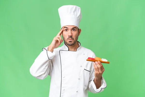Jeune Chef Caucasien Tenant Sushi Sur Fond Isolé Penser Une — Photo