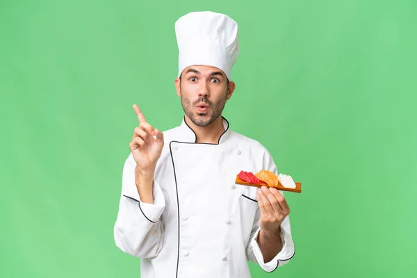 Junger Kaukasischer Koch Hält Ein Sushi Über Isolierten Hintergrund Und — Stockfoto
