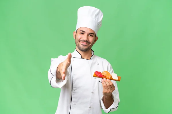 Ung Kaukasisk Kock Håller Sushi Över Isolerad Bakgrund Skakar Hand — Stockfoto
