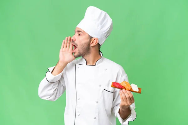 Young Caucasian Chef Holding Sushi Isolated Background Shouting Mouth Wide — Stock Photo, Image