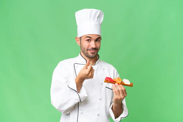 Jonge Kaukasische Chef Houdt Een Sushi Geïsoleerde Achtergrond Het Maken — Stockfoto