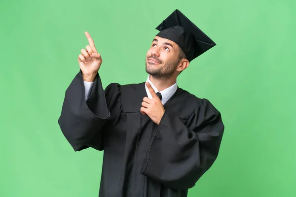 Νεαρός Απόφοιτος Πανεπιστημίου Άνθρωπος Πάνω Από Απομονωμένο Υπόβαθρο Δείχνοντας Δείκτη — Φωτογραφία Αρχείου