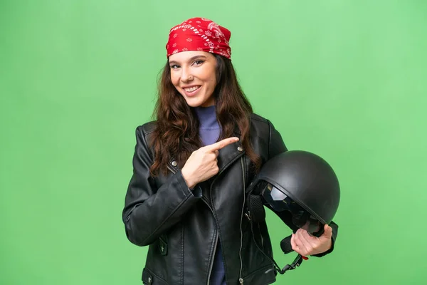 若いですCaucasian女性とともにオートバイヘルメット上の隔離された背景を指す側に製品を提示します — ストック写真