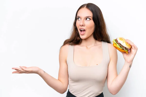 Młoda Kaukaska Kobieta Trzyma Hamburgera Izolowane Białym Tle Zaskoczeniem Wyraz — Zdjęcie stockowe