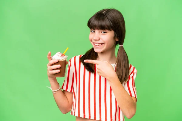 Stock image Young man with chocolat milkshake over isolated background and pointing it