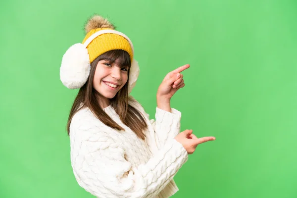 一个带着冬衣的高加索小女孩披着孤立的背景 手指指向旁边 展示了一种产品 — 图库照片