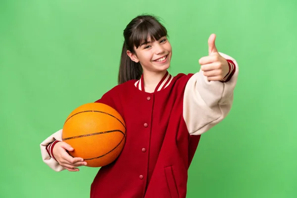 小さなCaucasian女の子遊びバスケットボール上の隔離された背景与えますA親指アップジェスチャー — ストック写真
