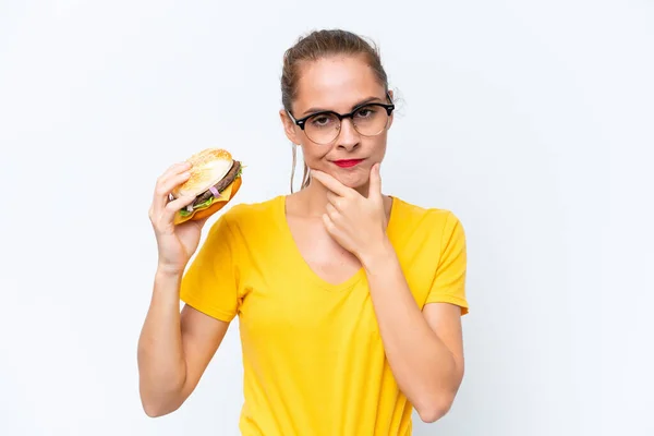 Młoda Kaukaska Kobieta Trzyma Hamburgera Białym Tle Myśląc — Zdjęcie stockowe