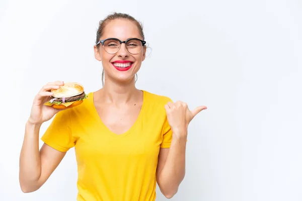Young Caucasian Woman Holding Burger Isolated White Background Pointing Side — Zdjęcie stockowe