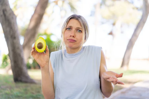 Junge Blonde Frau Hält Draußen Eine Avocado Und Macht Beim — Stockfoto