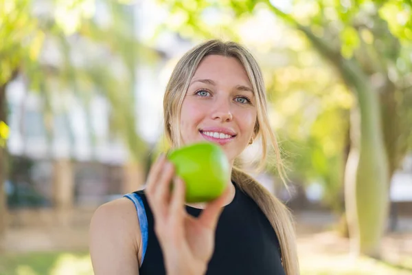 Joven Mujer Rubia Aire Libre Sosteniendo Una Manzana Con Expresión — Foto de Stock