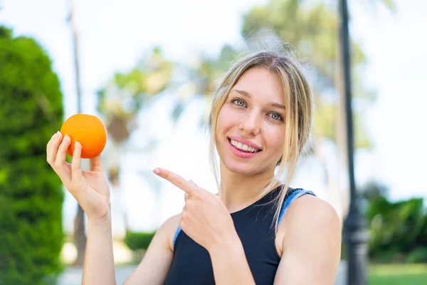 Junge Blonde Sportlerin Hält Draußen Eine Orange Der Hand Und — Stockfoto