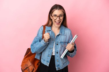 Pembe arka planda izole edilmiş genç beyaz kadın galibiyeti kutluyor.