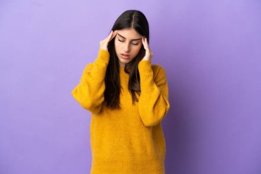 Mor arka planda başağrısı olan genç beyaz bir kadın.
