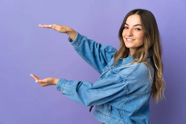 被隔离在紫色背景下的年轻罗马尼亚妇女 手持版权空间插入广告 — 图库照片