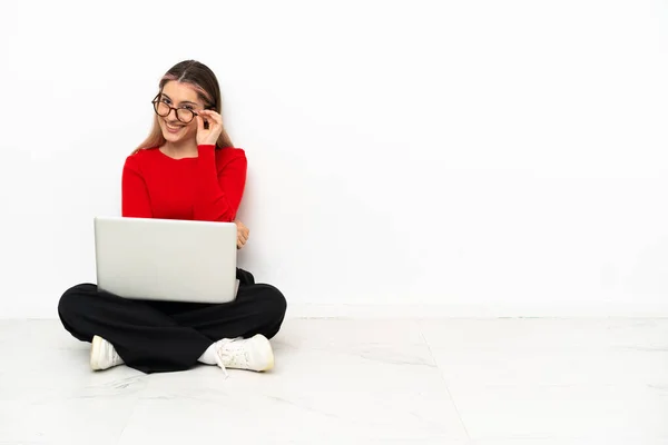 年轻的高加索女人 带着笔记本电脑坐在地板上 戴着眼镜 快乐极了 — 图库照片