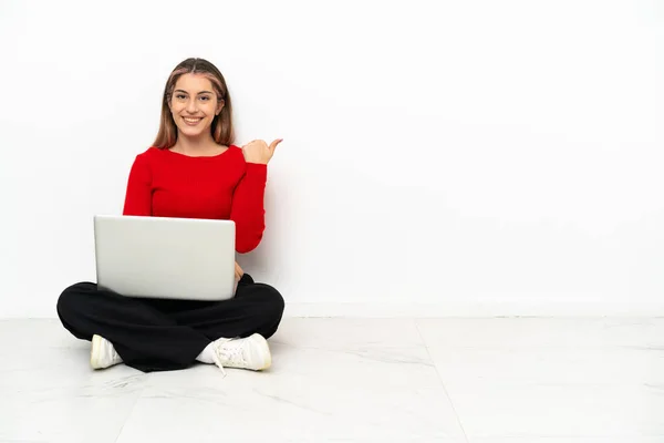 Young Caucasian Woman Laptop Sitting Floor Pointing Side Present Product — Stockfoto
