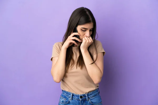 Молодая Кавказская Женщина Пользующаяся Мобильным Телефоном Фиолетовом Фоне Сомневается — стоковое фото