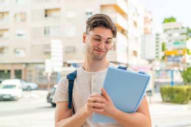 Dışarıda üzgün bir ifadeyle genç ve yakışıklı bir öğrenci.