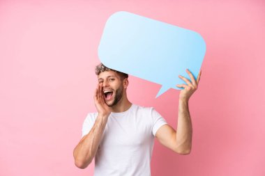 Pembe arka planda izole edilmiş yakışıklı beyaz adam boş bir konuşma balonu tutuyor ve bağırıyor.
