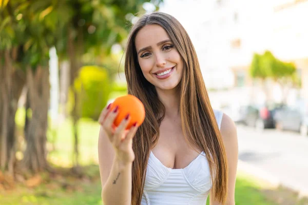 年轻女子站在户外 满脸喜色地捧着橙子 — 图库照片