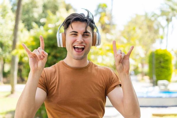 Jovem Homem Bonito Ouvindo Música Fazendo Gesto Rock — Fotografia de Stock