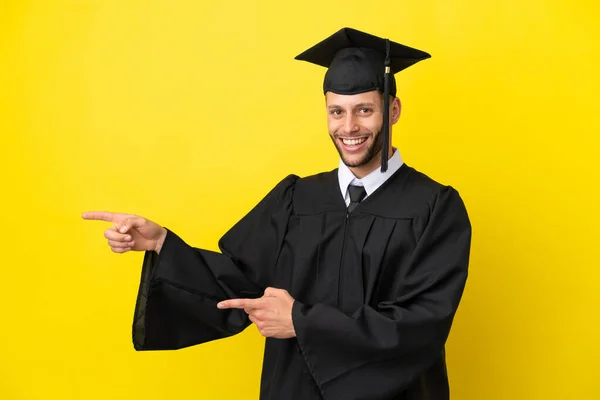 Junger Universitätsabsolvent Kaukasischer Mann Isoliert Auf Gelbem Hintergrund Zeigt Mit — Stockfoto