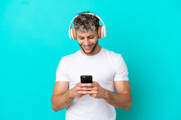Jovem Bonito Caucasiano Homem Isolado Fundo Azul Ouvir Música Olhando — Fotografia de Stock