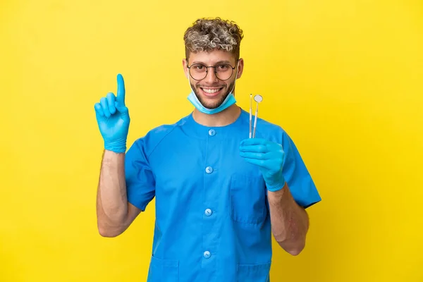 Dentista Caucasiano Homem Segurando Ferramentas Isoladas Fundo Amarelo Apontando Para — Fotografia de Stock