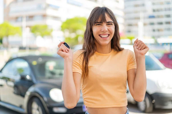 屋外で車のキーを保持し 勝利を祝う若い女性 — ストック写真