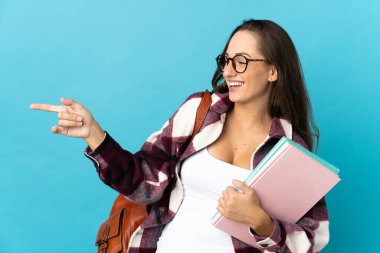 İzole edilmiş arka planda genç bir bayan parmak göstererek bir ürün sunuyor.